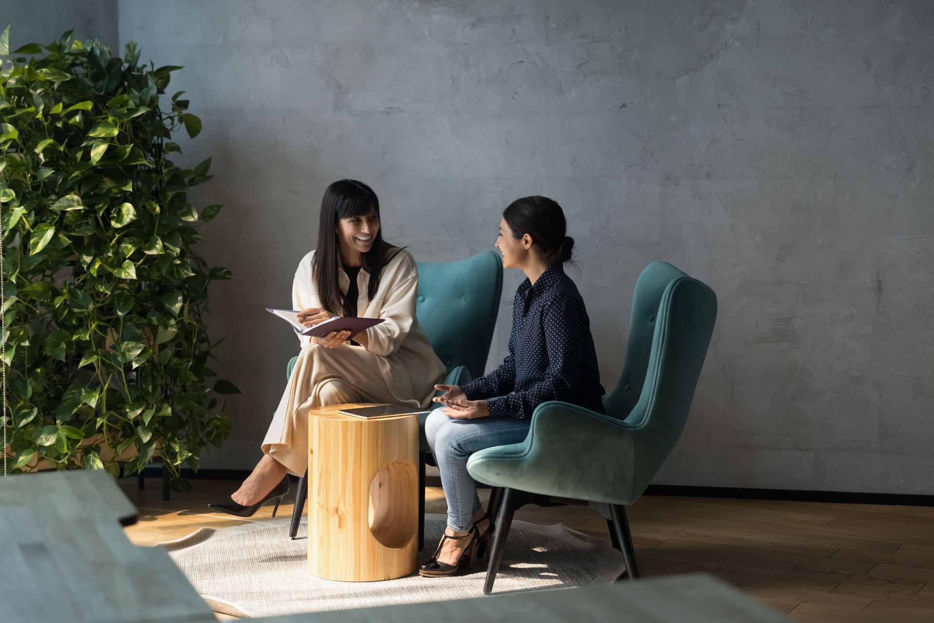 Friendly colleagues seated in armchairs enjoy talk in office space
